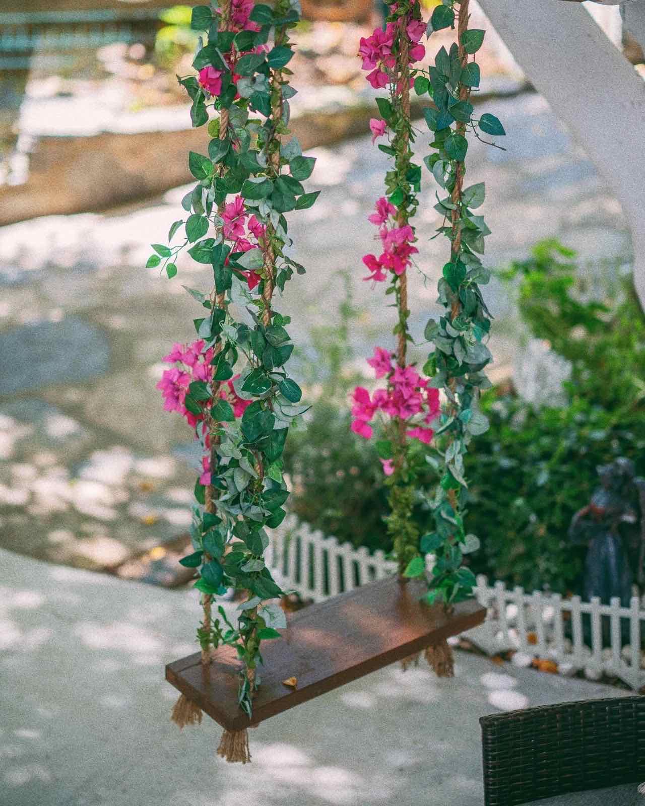 Pembe begonvillerle sarılı ahşap bahçe salıncağı